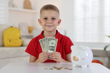 Cep harçlığı ve kumbarası olan küçük bir çocuk.