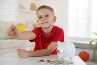 Cep harçlığı ve kumbarası olan küçük bir çocuk.
