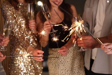 Yeni yılı evde maytap ve şarap kadehleriyle kutlayan arkadaşlar, yakın plan.