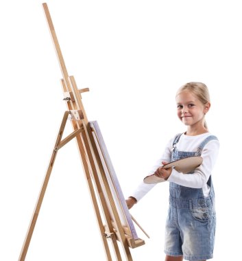 Meslek seçimi. Beyaz arka planda ressammış gibi davranan palet boyalı ve sehpanın yanındaki fırçalı küçük kız.