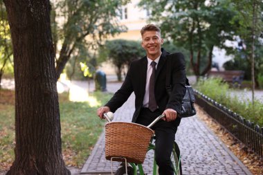 Sokakta bisiklet süren takım elbiseli bir adam.