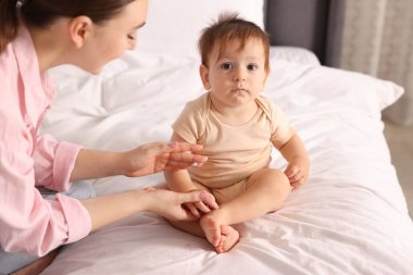 Anne evde bebeğinin vücuduna krem sürüyor.