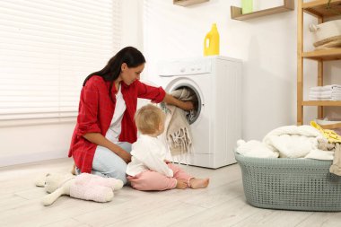 Ev hanımı ve bebeği evde çamaşır yıkıyor.