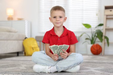 Evde cep harçlığı tutan küçük çocuk.