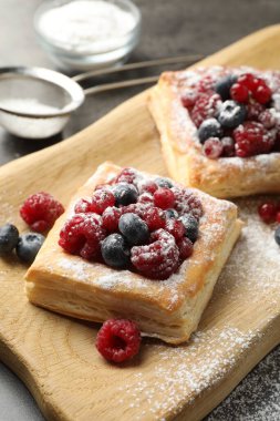 Böğürtlenli ve pudra şekerli lezzetli börekler gri masada, yakın plan.