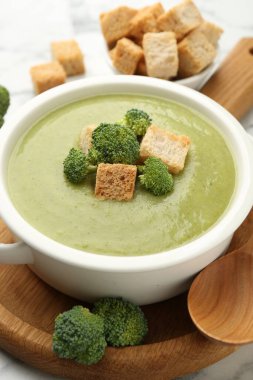 Tasty broccoli cream soup with croutons served on table, closeup