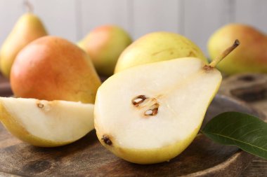 Whole and cut fresh pears on wooden table, closeup