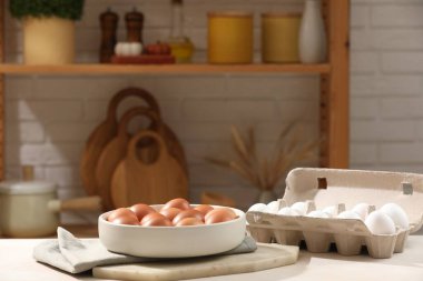 Tabakta çiğ tavuk yumurtası ve mutfakta beyaz masada karton. Metin için boşluk