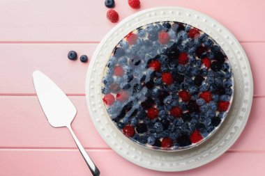 Delicious cheesecake with berries served on pink wooden table, flat lay