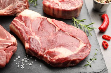 Gri masada çiğ et ve baharat parçaları, yakın plan.