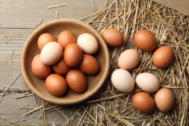 Tabakta çiğ tavuk yumurtası ve ahşap masada saman, düz yatıyordu.