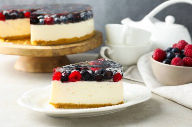 Piece of delicious cheesecake with berries and mint on light grey table, closeup