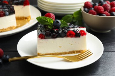 Lezzetli peynirli kek, böğürtlenli ve nane şekerli, siyah ahşap masa, yakın plan.