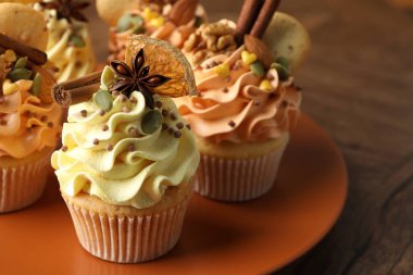 Renkli kremalı lezzetli kekler, baharatlar, kurabiyeler ve fındıklar ahşap masada, yakın plan.