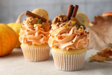 Renkli kremalı, baharatlı, kurabiyeli, fındıklı ve sonbahar desenli kapkekler gri masada, yakın plan.