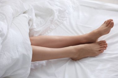Beyaz çarşaflı, çıplak ayaklı bir kadın, yakın plan.