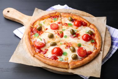 Delicious pizza with cheese, tomatoes and olives on black wooden table, closeup