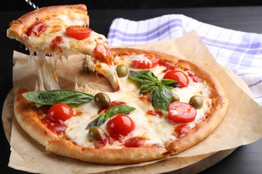 Gri masada peynirli, domatesli ve zeytinli lezzetli bir pizza yemek.