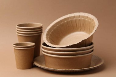 Set of disposable tableware on brown background, closeup