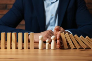 Risk. Tahta masada insan figürlerini domino etkisinden koruyan adam, yakın plan.