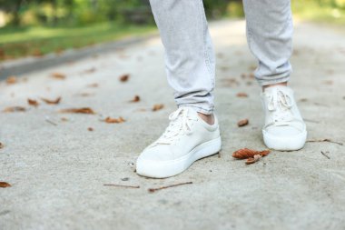 Havalı spor ayakkabılı bir adam asfaltta yürüyor, yakın plan. Metin için boşluk