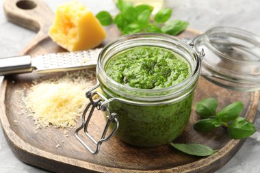 Kavanozda taze pesto sosu, gri masada rende ve malzemeler, yakın plan.
