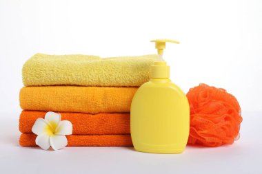 Taze havlu yığını, kozmetik ürünler, sünger ve plumeria çiçeği beyaza izole edilmiş.