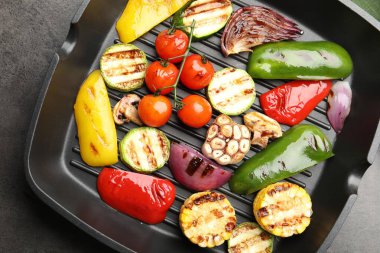 Gri masada ızgara sebze ve baharatlı tava, üst manzara.