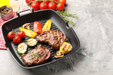 Izgara biftek, mantar, sebze ve baharatlı tava. Gri desenli masa, yakın plan. Metin için boşluk