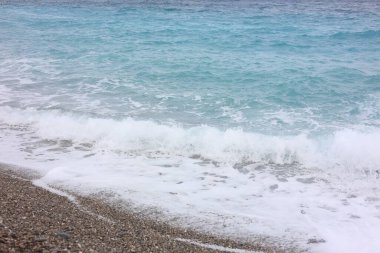 Dalgalı deniz manzarası ve kumsaldaki çakıl taşları.