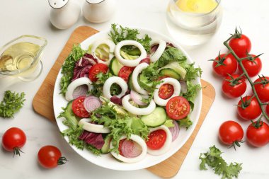 Delicious salad with squid rings and vegetables served on white marble table, flat lay