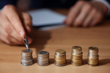 İçerideki ahşap masada madeni paraları sayan adam, seçici odaklanma