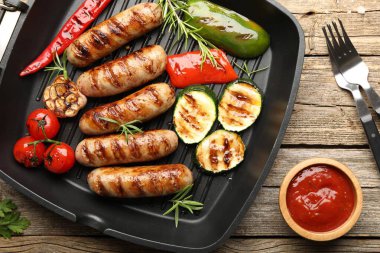Tavada ızgara sosis, sebze, baharat ve ahşap masada sos.