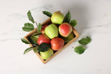 Fresh ripe apples in crate on white table, top view