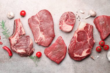 Çiğ et parçaları, baharatlar ve domatesler gri masada, düz yatıyordu.