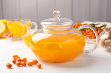 Sea buckthorn tea and fresh berries on white wooden table, closeup