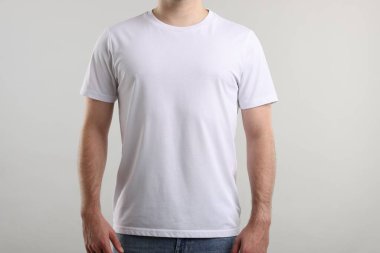 Açık gri arka plan yakınlarında şık beyaz tişörtler giyen genç adam, yakın plan. Tasarım için model