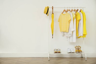 Beyaz duvarın yanında şık kıyafetler, ayakkabılar ve aksesuarlar, metin için yer.