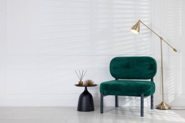 Şık bir lamba, rahat bir koltuk ve beyaz duvarın yanında dekorasyon masası. Metin için boşluk
