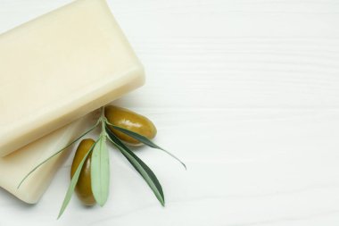 Zeytin ve yeşil yapraklı doğal sabun barları beyaz ahşap masada, yakın plan. Metin için boşluk