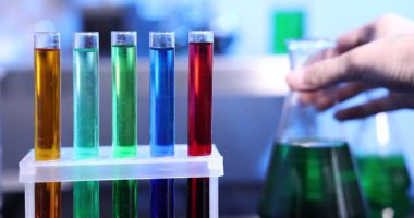 Camın içindeki renkli sıvılı kadın laboratuardaki masada, yakın plan.