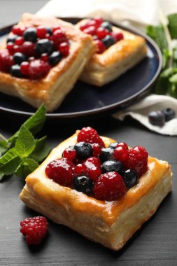 Gri ahşap masada meyveli ve nane şekerli lezzetli puf börekler, yakın plan.