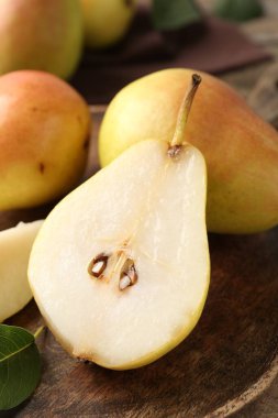 Whole and cut fresh pears on wooden table, closeup
