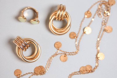 Hafif arka planda altın takıların şık sunumu, düz yatış