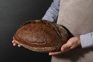 Siyah arka planda taze ekmeği olan fırıncı, yakın plan.