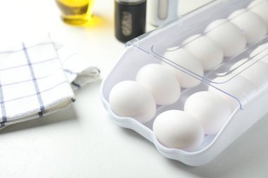 Beyaz masadaki kabın içinde çiğ tavuk yumurtası, yakın plan.