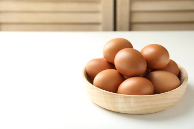 Beyaz masadaki kasede çiğ tavuk yumurtası, yakın plan. Metin için boşluk