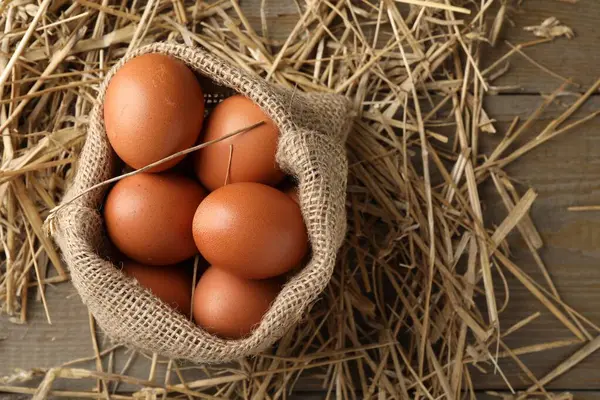 Çuval çuvalında çiğ tavuk yumurtası ve ahşap masada saman, üst manzara. Metin için boşluk