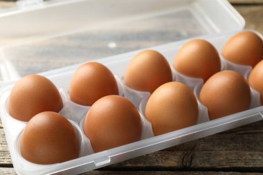 Ahşap masadaki kabın içinde çiğ tavuk yumurtası, yakın plan.