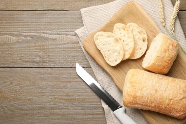 Taze çıtır ciabatalar, buğday kulakları ve tahta masa üzerinde bıçak, düz yatış. Metin için boşluk